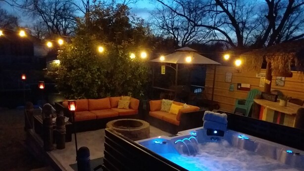 Ein Terrassenbereich im Freien mit Whirlpool, orangenen Sofas und Lichterketten.