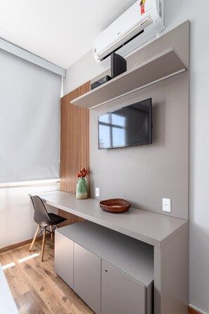 A modern kitchen with a built-in stove, a flat-screen TV mounted on the wall, and a wooden panel accent.
