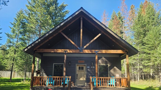 A lodge with a wooden exterior, a porch with blue chairs, and a gravel driveway.