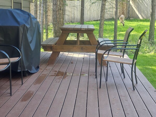 A wooden deck with a picnic table and metal chairs.
