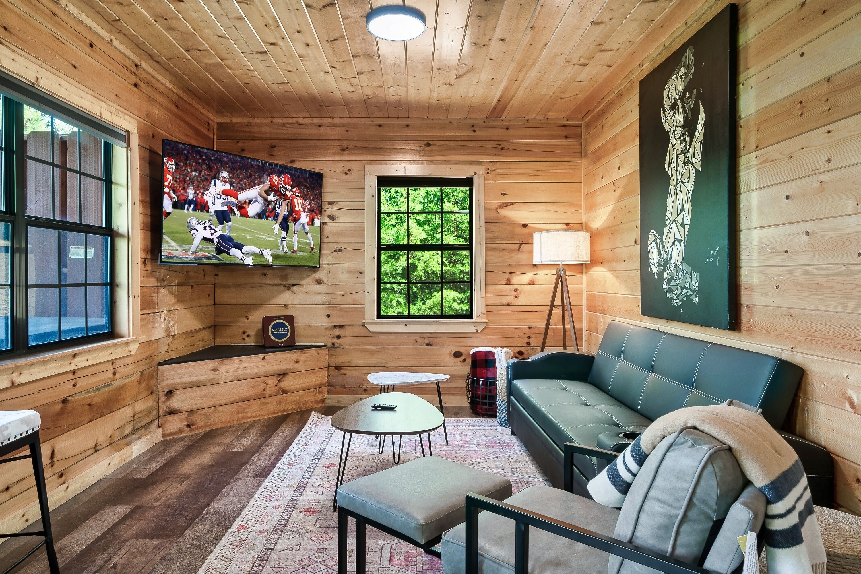 Ein gemütliches Blockhäuschen im Inneren mit Fernseher, Holzwänden, einer Couch und einem Fenster.
