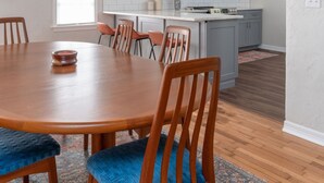A modern kitchen with white cabinets, a wooden dining table, and blue upholstered chairs.