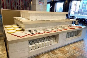 A buffet setup with multiple serving trays and utensils. - Xinhao Business Hotel (Yichun)