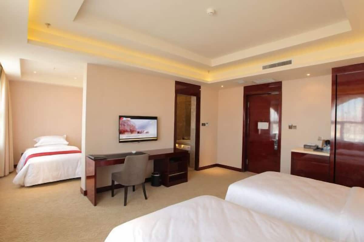 A hotel room with two beds, a desk, a television, and a wardrobe.