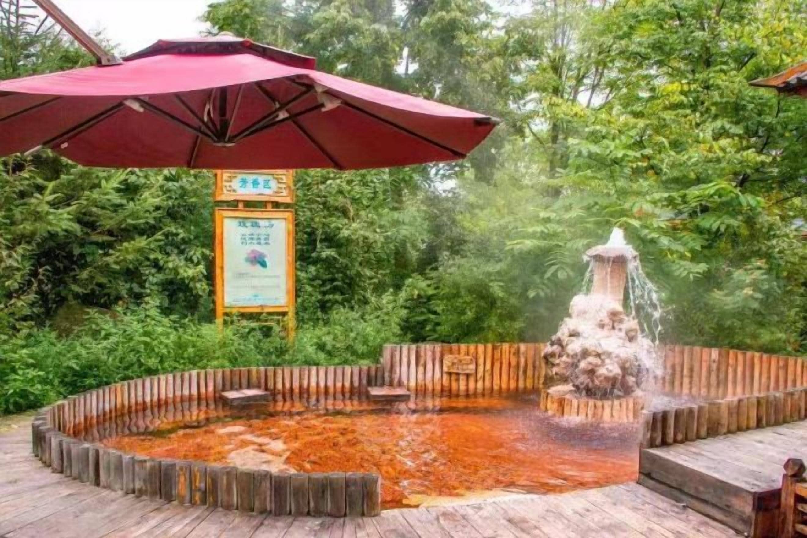 Un espace de sources chaudes doté d’une terrasse en bois, d’une clôture en bois et d’une fontaine.