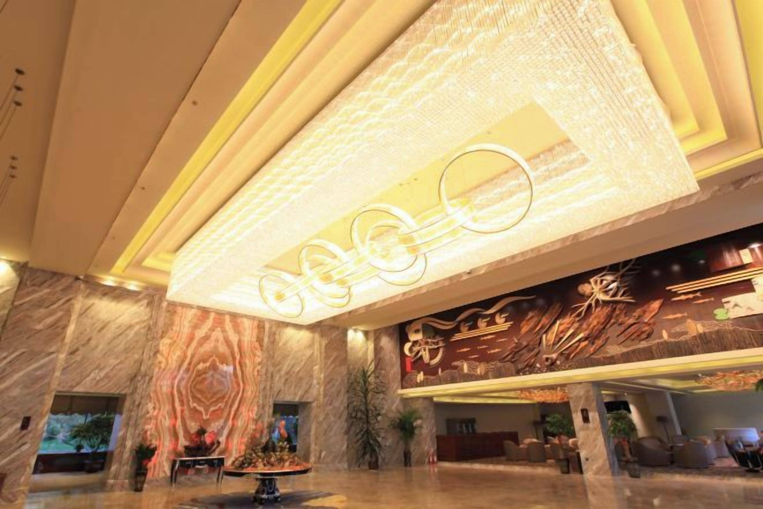 Un hall de hotel con suelo de mármol, una recepción y un gran cartel iluminado.