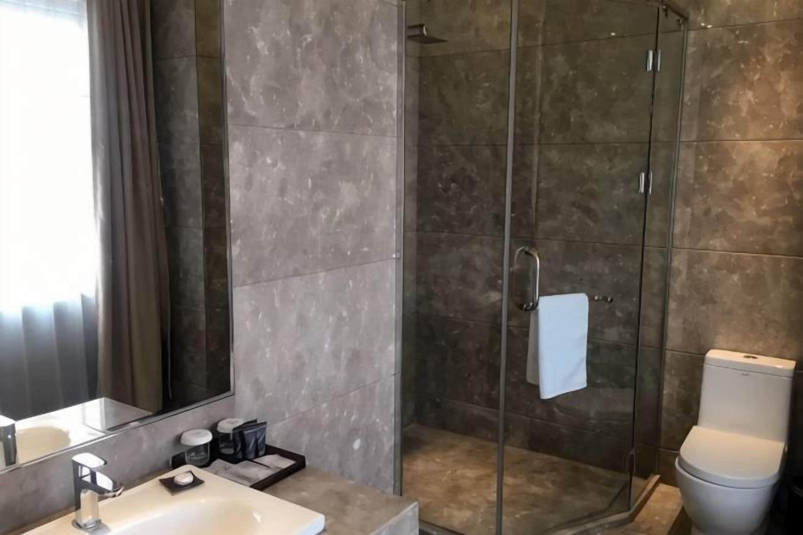 A modern bathroom with a glass-enclosed shower, a sink with a mirror, and a toilet.