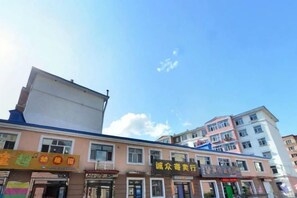A multi-story building with various storefronts on the ground floor. - Xinhao Business Hotel (Yichun)