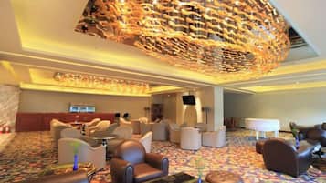 A spacious lobby with leather seating, a large chandelier, and a patterned carpet.