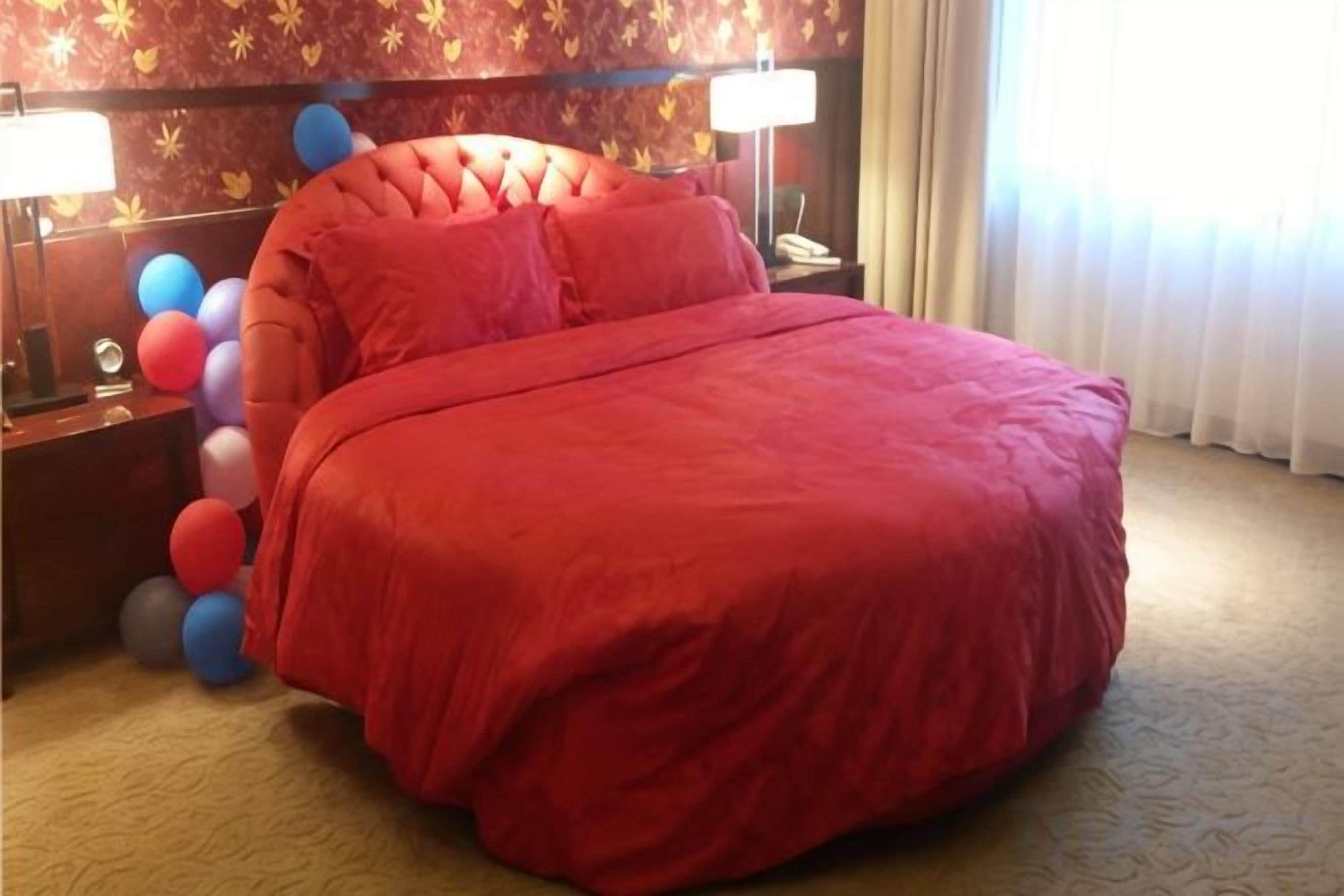 Una habitación con una cama grande, dos mesitas de noche con lámparas y una pared con estampado floral.