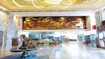A spacious lobby with a marble floor, a central fountain, and a large wall mural.