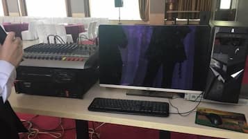 A computer setup with a mixer, monitor, keyboard, and mouse on a desk.