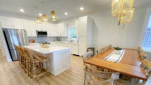 A modern kitchen with white cabinets, stainless steel appliances, and a wooden dining table with chairs. - Ocean block Townhouse with private pool and elevator (Ocean City)