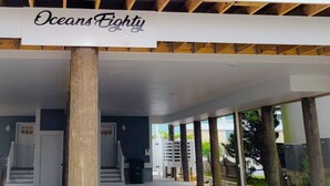 A two-story building with a covered porch and a sign reading "Oceans Eighty". - Ocean block Townhouse with private pool and elevator (Ocean City)
