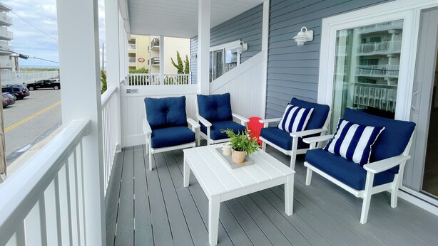 A covered porch with white furniture and a view of the street. - Ocean block Townhouse with private pool and elevator (Ocean City)