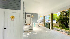 A covered porch with a concrete floor, a white door, and a 'Surfer Crossing' sign. - Ocean block Townhouse with private pool and elevator (Ocean City)