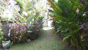 A garden pathway with lush greenery and a stone wall. - Salty Sea Guesthouse (Jimbaran)