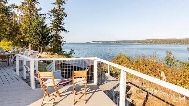 Eine Terrasse mit Blick auf einen See, umgeben von Bäumen und einem weißen Geländer.