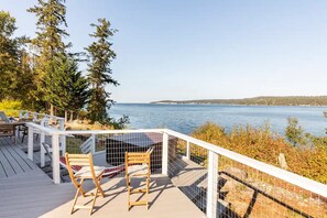 Une terrasse avec vue sur un lac, entourée d’arbres et dotée d’une balustrade blanche.