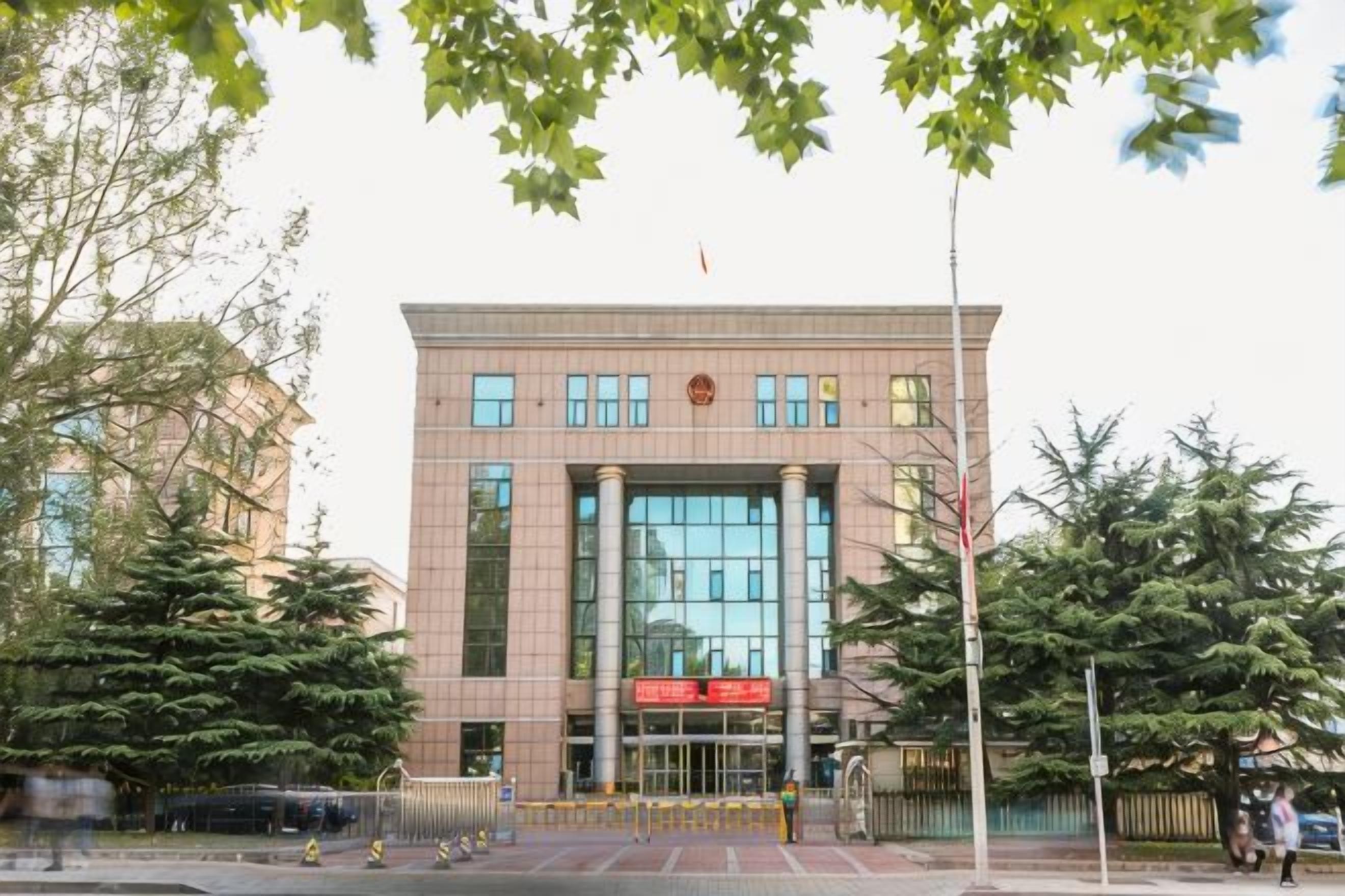 A building with a large glass facade, a red sign, and a flag on top.
