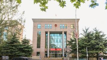 A building with a large glass facade, a red sign, and a flag on top.