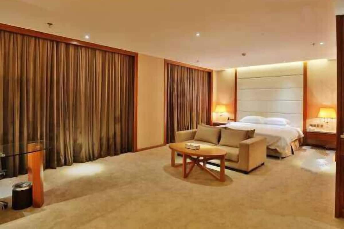 A hotel room with a bed, a sofa, a coffee table, and curtains.