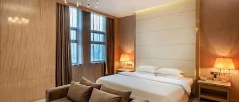 A hotel room with a bed, a sofa, a chandelier, and two bedside lamps.