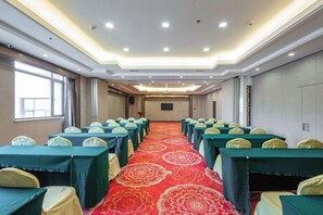 A conference room with rows of tables and chairs, a patterned carpet, and a long table at the front. - HR-East Hotel (Dalian)