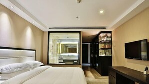 Una habitación de hotel con cama, televisión, escritorio y espejo.