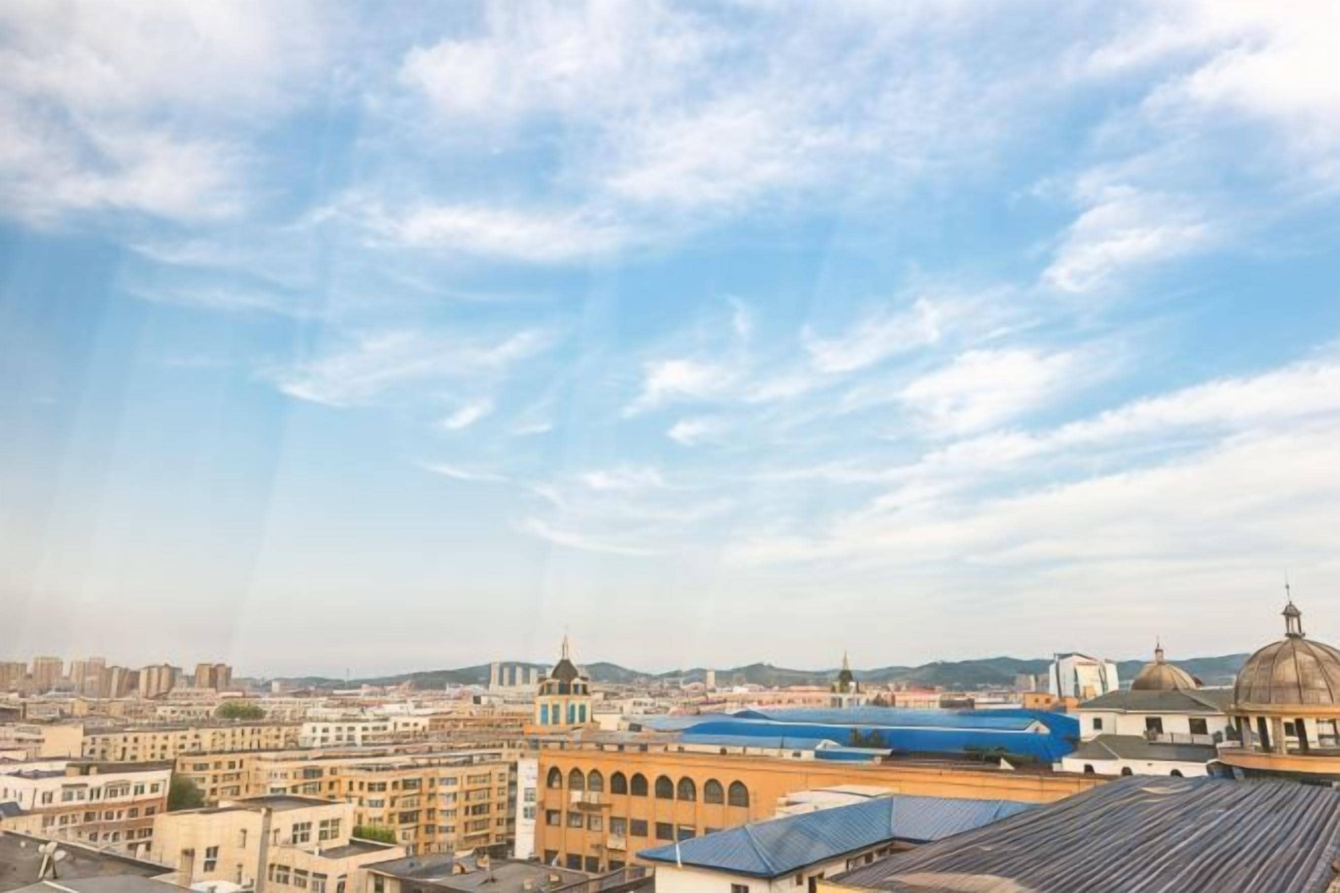 A cityscape with buildings, a dome, and a blue structure.