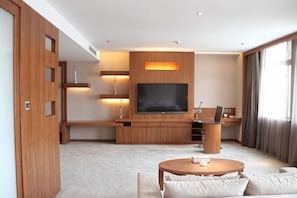 A modern living room with a large flat-screen TV, wooden furniture, and a cozy seating area. - HR-East Hotel (Dalian)