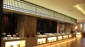 Zona de bufé con varias estaciones de servicio, un chef y un diseño interior moderno.