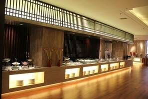 Zona de bufé con varias estaciones de servicio, un chef y un diseño interior moderno.