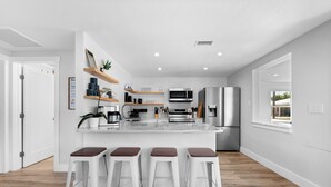 A modern kitchen with a central island, bar stools, and built-in appliances. - Walk to Beach. Beautifully Renovated 3BR, 2BA Home w/Outdoor Shower & Grille (Nokomis)