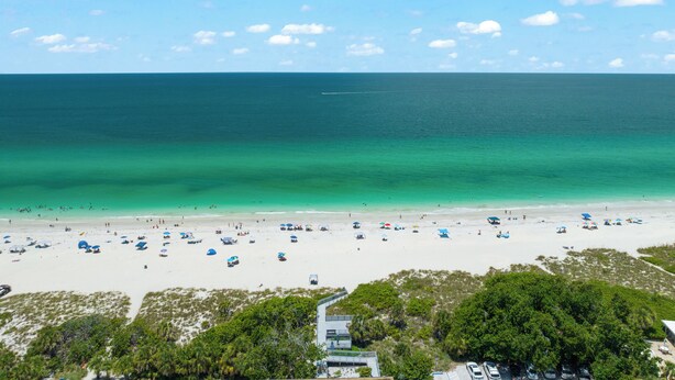A beach with clear turquoise waters, a sandy shore, and scattered umbrellas. - Walk to Beach. Beautifully Renovated 3BR, 2BA Home w/Outdoor Shower & Grille (Nokomis)