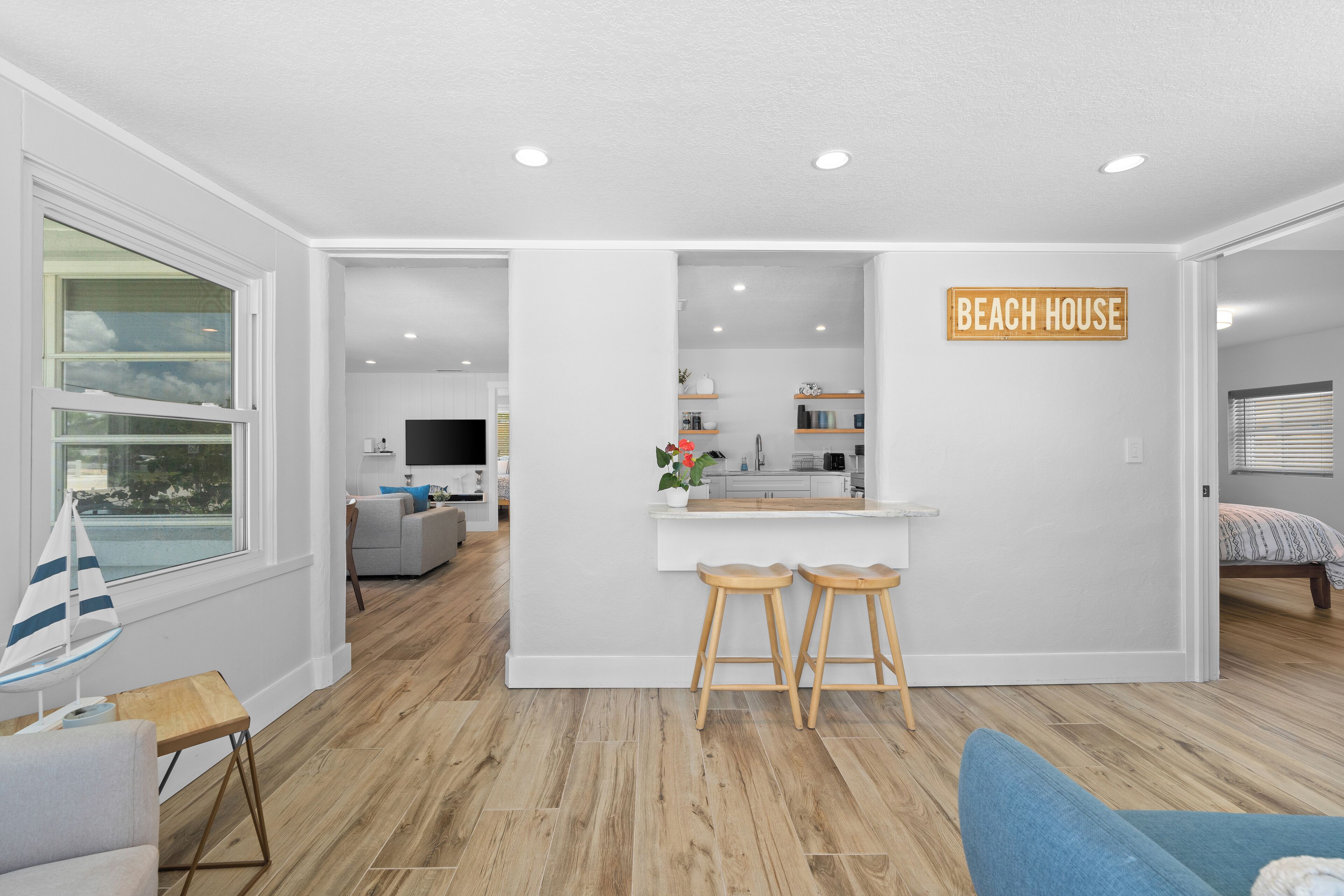 A modern living room with a kitchen area, a dining space, and a bedroom.