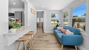A modern kitchen with a white countertop, wooden stools, and a potted plant. - Walk to Beach. Beautifully Renovated 3BR, 2BA Home w/Outdoor Shower & Grille (Nokomis)