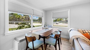 A dining area with a wooden table and chairs, a bench, and two windows with blinds. - Walk to Beach. Beautifully Renovated 3BR, 2BA Home w/Outdoor Shower & Grille (Nokomis)