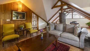 Un acogedor salón tipo loft con paredes de madera, una chimenea de piedra y un techo inclinado.