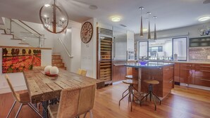 Een moderne keuken met houten vloeren, een centraal eiland en een eethoek met een houten tafel en stoelen.