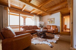 A cozy living room with leather sofas, a coffee table, and a large window.