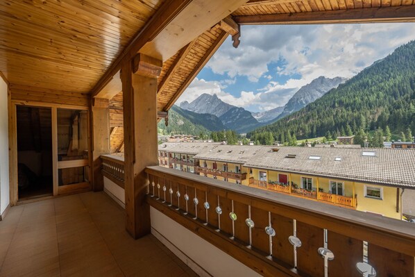 A wooden balcony with a view of a mountain landscape and a town below.
