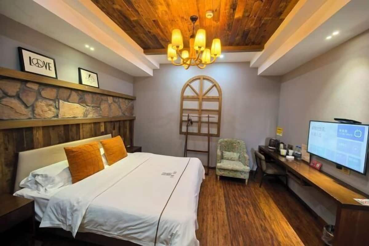 Une chambre d’hôtel avec un lit, un mur en pierre, un lustre, une télévision et un bureau.