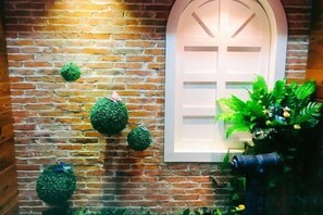 A brick wall with a white-framed window and decorative green spheres. - Bei'an Theme Hotel (Deqing)