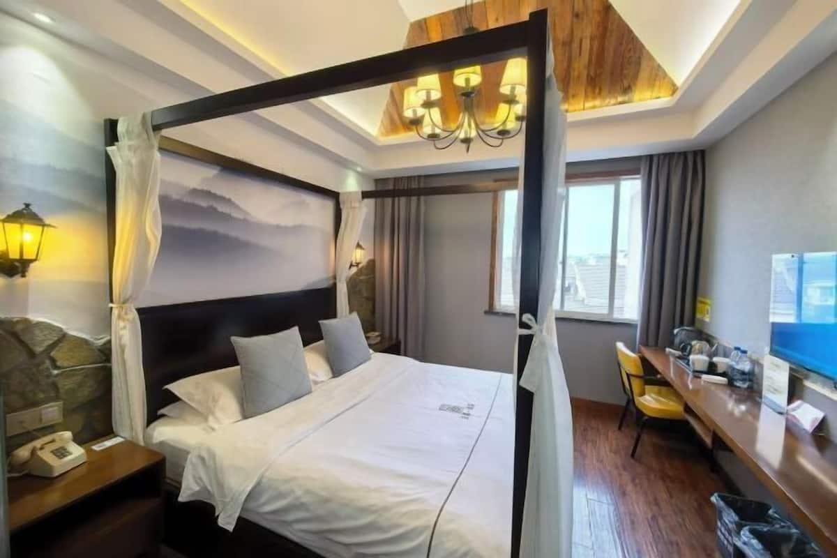Une chambre d’hôtel avec un lit, un bureau, une chaise, un téléphone et une fenêtre.