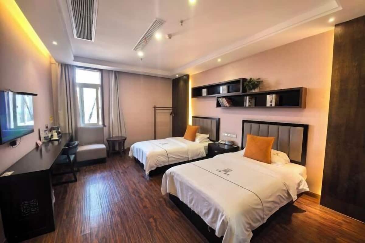 Une chambre d’hôtel avec deux lits, un bureau, une télévision et une bibliothèque.