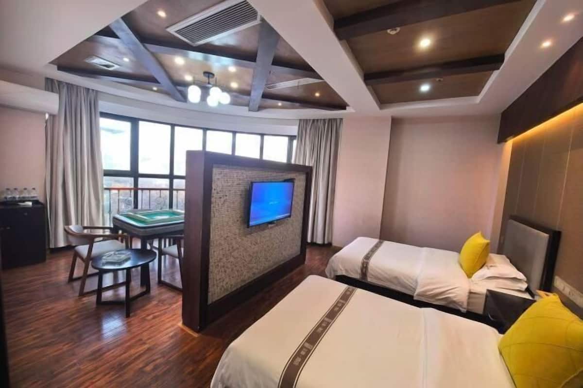 Une chambre d’hôtel avec deux lits, une télévision, un bureau et une vue sur l’extérieur.