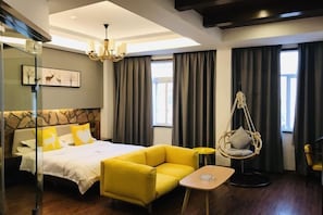 A modern hotel room with a large bed, a yellow sofa, a hanging chair, and a small table. - Bei'an Theme Hotel (Deqing)