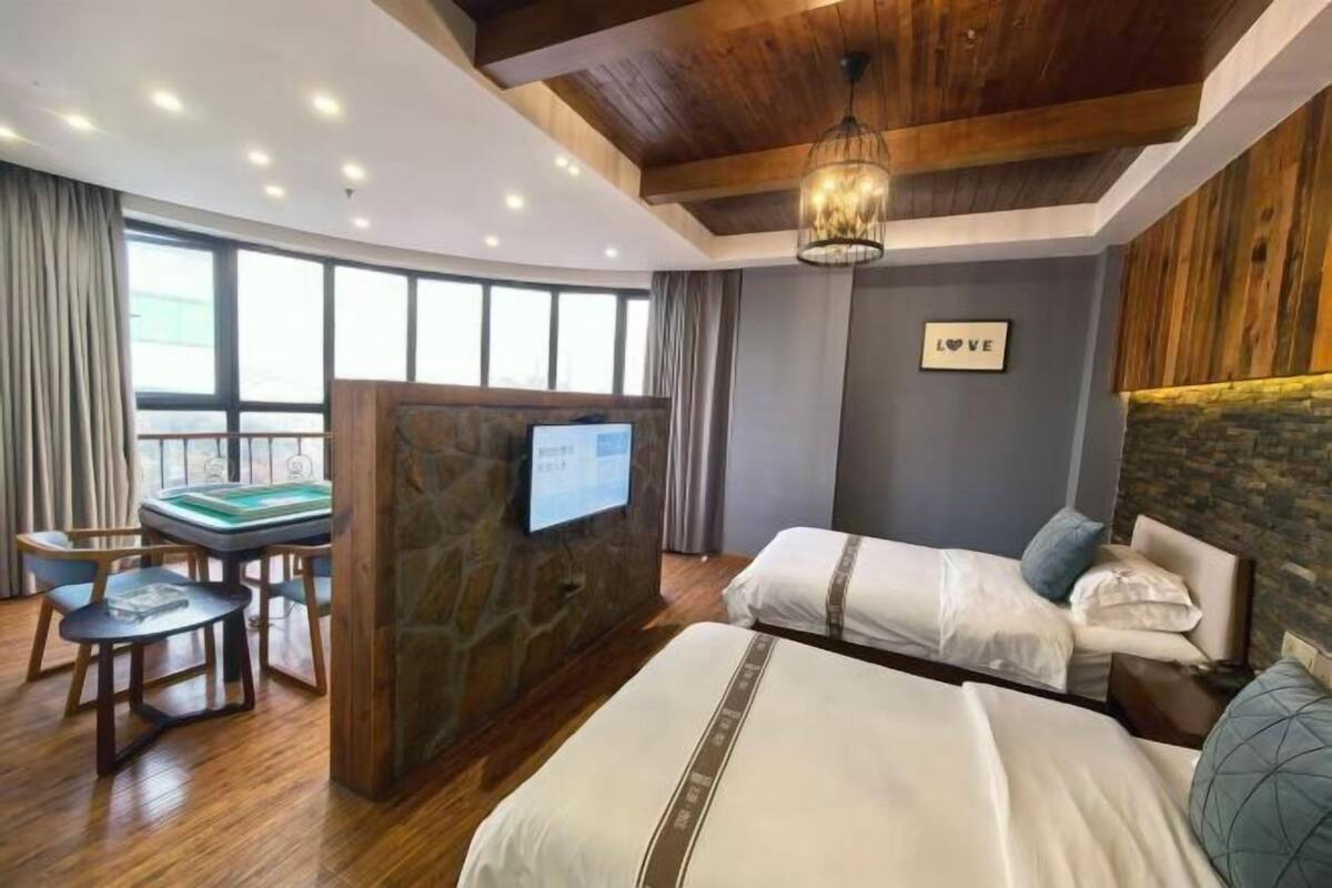 Une chambre d’hôtel avec deux lits, un bureau avec un ordinateur et une grande fenêtre.