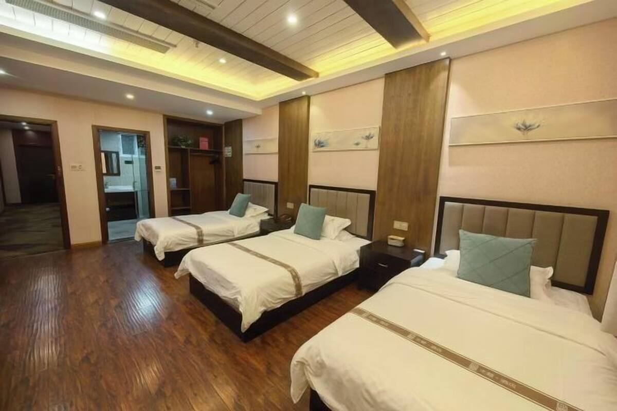 Une chambre d’hôtel avec trois lits, un plancher en bois et un design moderne au niveau du plafond.